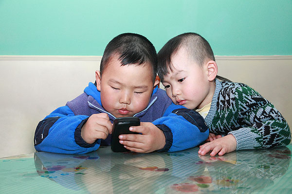 两个玩手机的小男孩